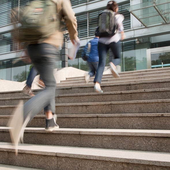 blurry image of students walking up stairs to building