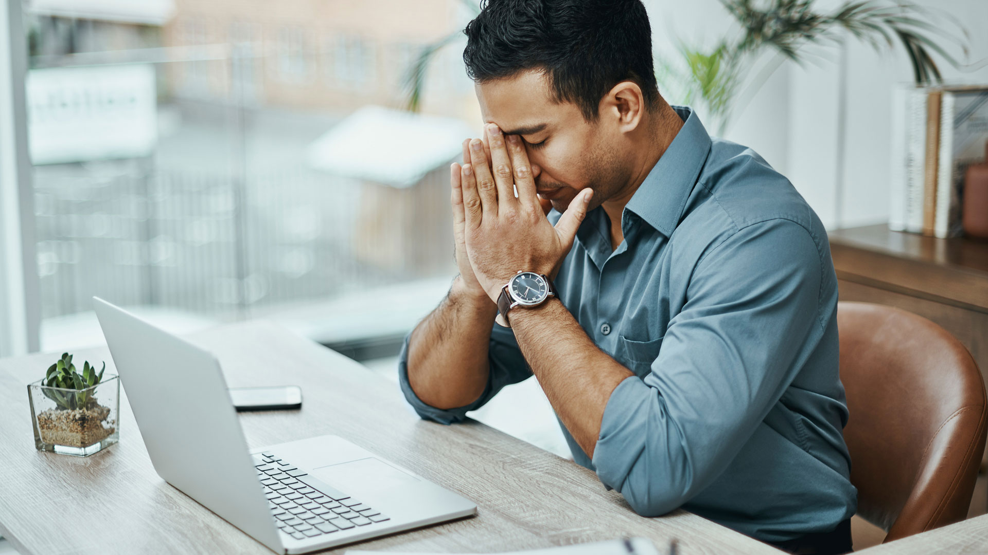 employee sitting at desk with head in hands