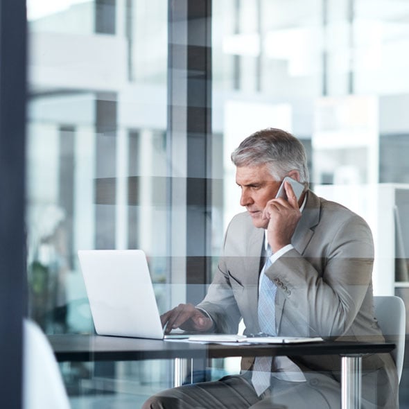 man on the phone sitting at his computer