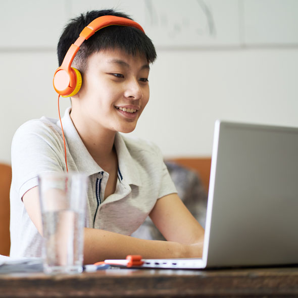 Teenage male at laptop with headphones on
